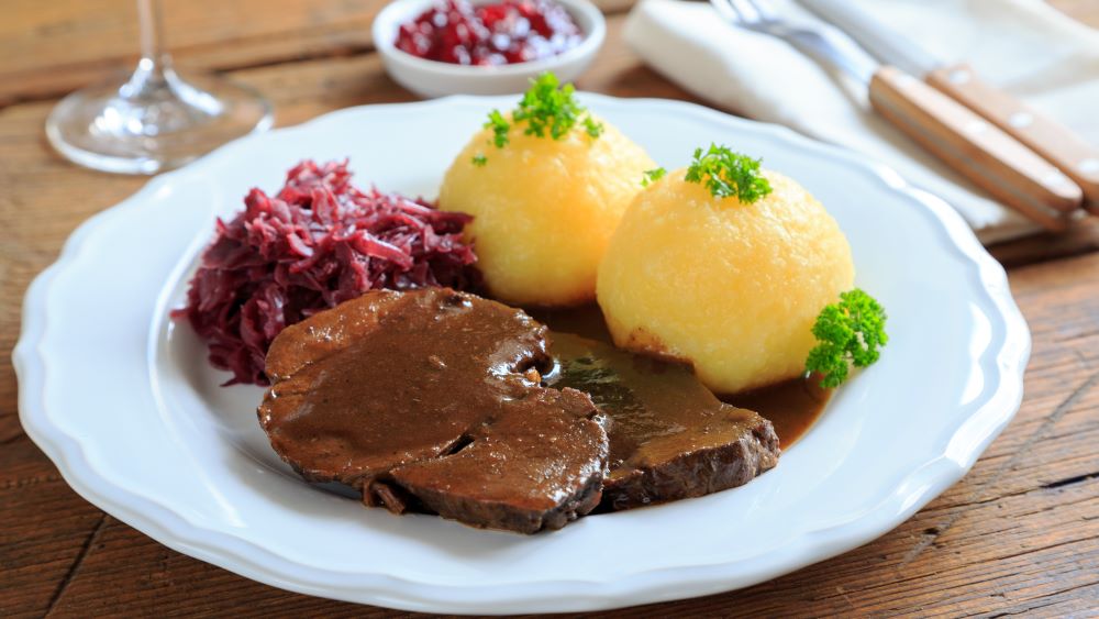 Burgunderbraten mit Klößen und Rotkohl auf einem Teller.